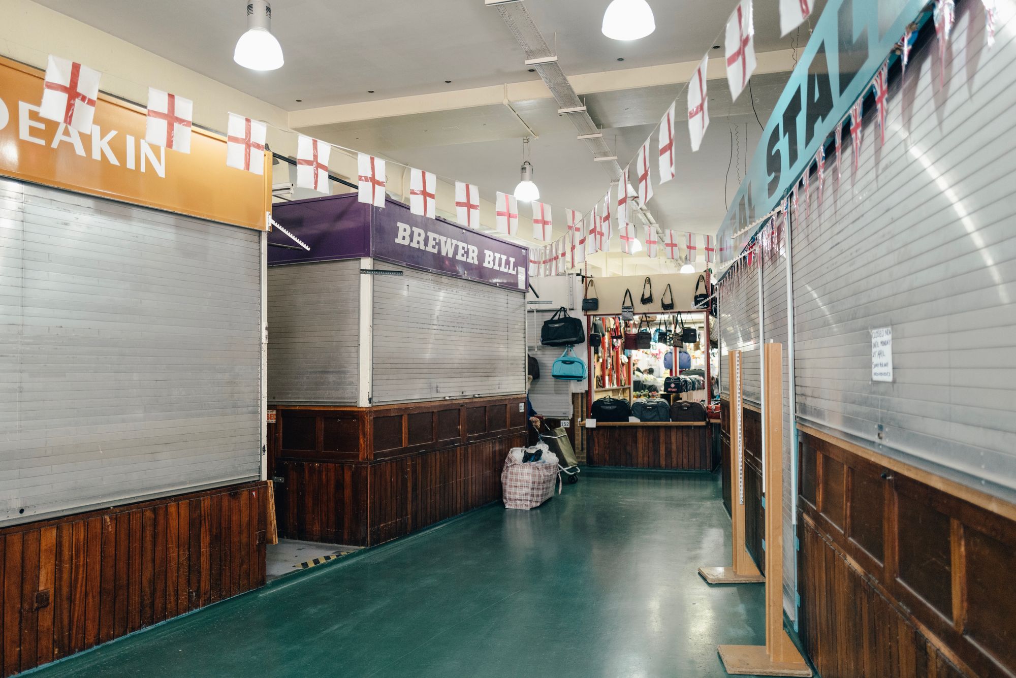 Closed market stalls in Coventry, with patriotic England flags adorning the ceiling.