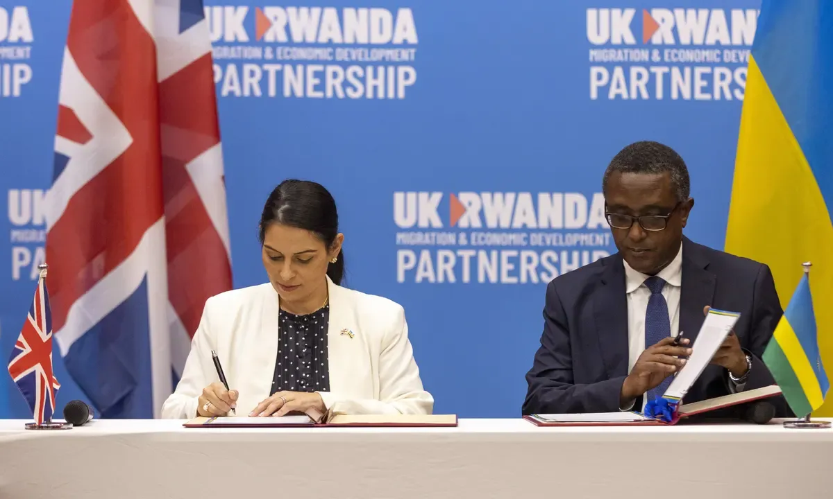 UK and Rwandan government officials signing an agreement.